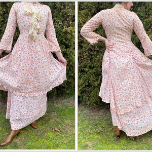 May include: A white dress with a floral print in shades of orange and blue. The dress has a ruffled neckline and long sleeves. The dress is layered and has a tiered skirt.