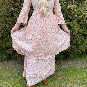 May include: A white dress with a floral print in shades of orange, blue, and white. The dress has a ruffled neckline and a tiered skirt.