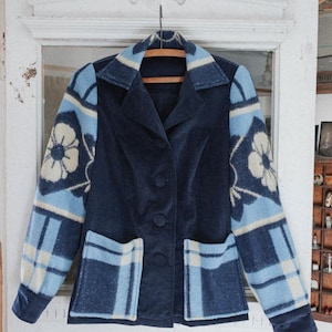 May include: A navy blue corduroy jacket with a plaid and floral pattern on the sleeves and pockets. The jacket has a button closure and a collar.