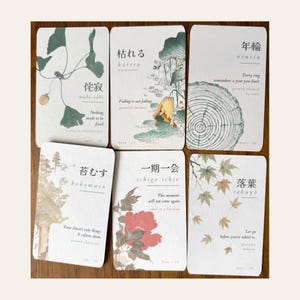 May include: Six rectangular cards featuring Japanese kanji, romanized text, and English phrases alongside botanical illustrations. Designs include ginkgo leaves, a tree ring, a red flower, and maple leaves in muted green, red, and brown tones.
