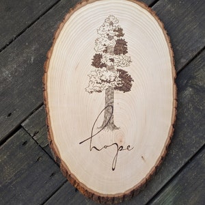 May include: A wooden tree slice with a woodburned image of a tree and the word "hope" underneath.