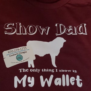 May include: Burgundy t-shirt with white text that reads "Show Dad The only thing I show is My Wallet". A white silhouette of a sheep is above the text. A business card with the text "Goodwin Designs" is in the bottom left corner.