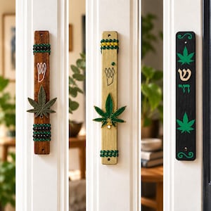 Puede incluir: Tres estuches de mezuzá rectangulares montados en marcos de puertas. El de la izquierda es de madera oscura con una hoja de metal y cuentas. El central es de madera clara con una hoja verde y cuentas. El de la derecha es de madera negra con estampados de hojas verdes y letras hebreas.