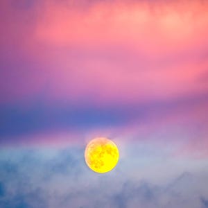 May include: A bright yellow full moon in a blue and pink sky with clouds. The moon is in the upper right corner of the image.