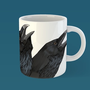 May include: White ceramic mug featuring a black and white illustration of two ravens facing each other. The ravens have black feathers and are looking to the right.