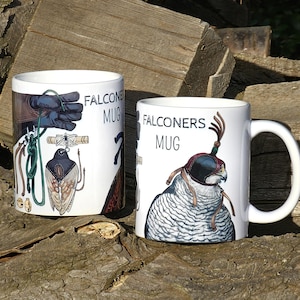 Może przedstawiać: Dwa białe ceramiczne kubki z ilustracjami przedstawiającymi sokolnictwo. Kubek po lewej stronie ma zielono-brązową ilustrację rękawicy sokolniczej, sokoła i sprzętu sokolniczego. Kubek po prawej stronie ma biało-brązową ilustrację sokoła w kapturze. Oba kubki mają nadrukowany tekst "Falconers Mug".