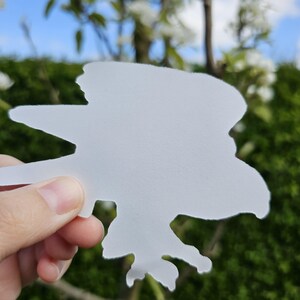May include: White vinyl sticker of a bird in flight. The sticker is cut out in the shape of a bird with its wings spread.