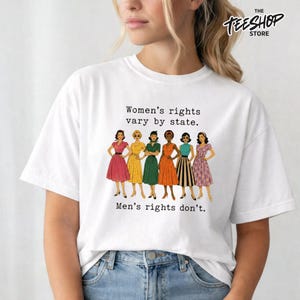 Könnte beinhalten: Ein weißes kurzärmeliges T-Shirt mit einer Grafik von sechs illustrierten Figuren in Vintage-Kleidern. Der Text darüber lautet "Women's rights vary by state." und der Text darunter "Men's rights don't." Das T-Shirt hat einen Rundhalsausschnitt.
