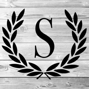 May include: Black monogram letter "S" inside a laurel wreath on a white and gray wooden background. The wreath is composed of stylized leaves. The wood grain adds a rustic texture to the design, creating a classic and elegant aesthetic.