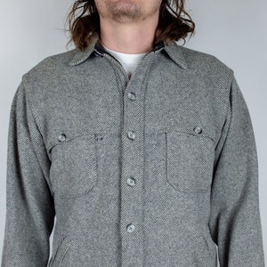 May include: A gray and white herringbone long-sleeve shirt with a button-up front and two chest pockets.