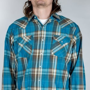 May include: A blue and brown checked long-sleeved shirt with a button-down collar and two chest pockets.