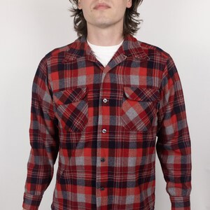 May include: A red, grey, and black plaid flannel shirt with a button-down collar and long sleeves.