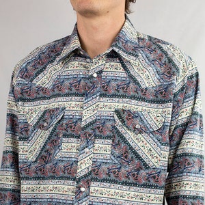 Puede incluir: Una camisa de manga larga con botones y un estampado paisley y floral en tonos azules, verdes, rosas y blancos.