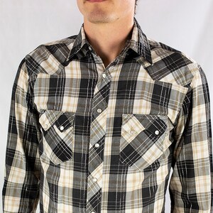 May include: A long-sleeved plaid shirt with a black and white checked pattern. The shirt has a button-down collar and two chest pockets.