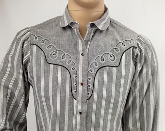 May include: A long-sleeved, striped button-down shirt with a western-style yoke and embroidery. The shirt is gray and white with a subtle texture.