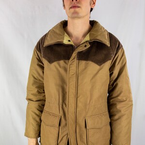 May include: A brown quilted jacket with a corduroy collar and pockets. The jacket has a zipper closure and a button flap.