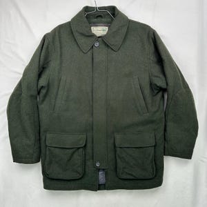May include: Dark green wool coat with a button-up front, two large front pockets, and a collared neckline. The coat has a classic design and the brand name "L.L.Bean" is visible on a tag on the collar.
