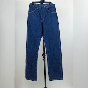 May include: A pair of dark blue denim jeans featuring a high-waisted design, a classic five-pocket construction, a metal button closure at the waist, and a zip fly. The jeans have straight legs with visible stitching along the seams and pockets.