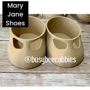 Könnte beinhalten: Ein Paar beigefarbene Mary Jane Schuhe mit glatter Textur, abgerundeter Zehenpartie und seitlichen Aussparungen. Das Bild enthält den Text 'Mary Jane Shoes' in einem schwarzen Kasten und den Social-Media-Namen '@busybeecabbies' auf der Vorderseite.