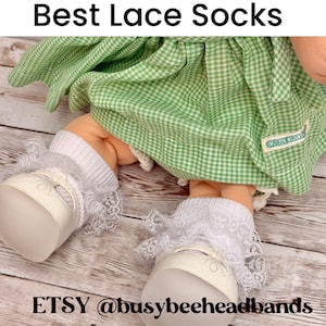 May include: White ankle socks featuring a delicate lace ruffle trim at the cuff, worn by a doll dressed in a green and white gingham dress. The text Best Lace Socks and ETSY @busybeeheadbands is visible in the image along with the doll.
