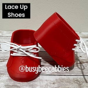 May include: A pair of bright red lace-up shoes featuring white laces and a smooth finish. The text "Lace Up Shoes" and "@busybeecabbies" is visible in the image. The shoes have a rounded toe design and a high-top silhouette with eyelets.