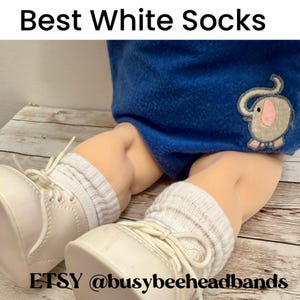 May include: A pair of white ribbed socks worn with white lace-up shoes and blue fabric featuring an embroidered elephant with pink ears. The text Best White Socks and ETSY @busybeeheadbands are visible at the top and bottom of the image.