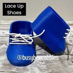 Może przedstawiać: Para jaskrawoniebieskich butów z białymi sznurowadłami, zawierająca napis Lace Up Shoes oraz nazwę @busybeecabbies. Buty mają gładką, formowaną konstrukcję z widocznymi oczkami i zaokrąglonym noskiem, prezentowane jako zestaw.