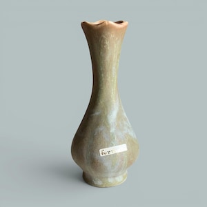 Peut inclure: Un vase en céramique avec un bord festonné et un col effilé, présentant un vernis moucheté dans des tons vert sauge, beige et crème. Une petite étiquette rectangulaire blanche avec le mot "form" imprimé en noir est apposée sur le bas du vase.