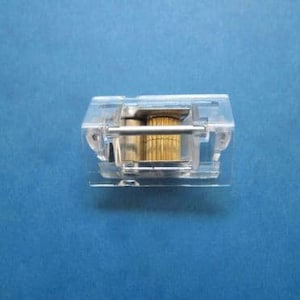 May include: A clear plastic roller blind mechanism with a gold metal roller inside.