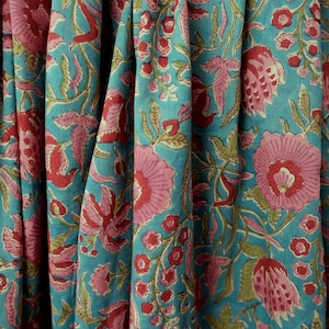 Peut inclure: Gros plan sur un tissu à motifs floraux. Le tissu est d'un bleu sarcelle vibrant, avec de grandes fleurs roses et des accents rouges. Des feuilles et des tiges vertes sont parsemées dans le motif, créant un textile vivant et coloré.