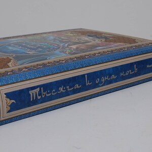 May include: A hardcover book with a blue and gold cover featuring ornate designs and text in a foreign language. The spine has text in a contrasting color. The book's edges are visible.
