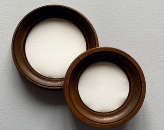 May include: Two round wooden picture frames with white mats. The frames are brown and have a simple design.