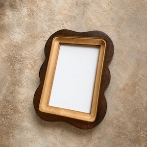 May include: A rectangular picture frame with a wavy, scalloped outer edge. The frame features a dark brown outer border and a lighter, natural wood-toned inner border surrounding a plain white rectangular center display area.