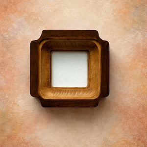 May include: A square wooden frame with a lighter square opening in the centre. The frame is a dark brown colour and has rounded corners. The background is a textured, mottled peach and brown.