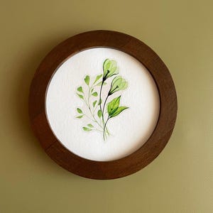 May include: A framed watercolor painting of delicate green flowers and leaves on a white background.