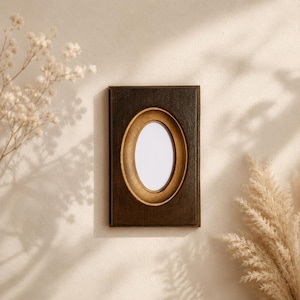 May include: A rectangular dark brown wooden picture frame featuring a central oval opening with a gold-toned inner border. The frame has a smooth, solid construction and is designed to hold a single photograph or artwork within its oval center.