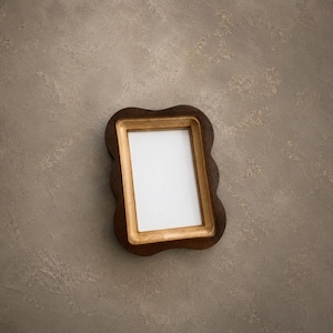 May include: A rectangular picture frame with a dark brown, scalloped outer edge and a smooth, light gold inner border. The frame features a vertical orientation and contains a plain white rectangular insert in the center for displaying a photograph.