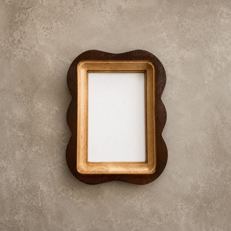 May include: A rectangular picture frame with a dark brown outer border and a lighter natural wood inner border. The frame features a distinct scalloped edge design on all four sides, surrounding a plain white rectangular center insert.