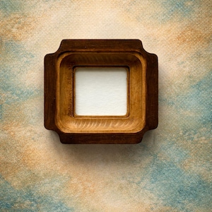 Può includere: Una cornice quadrata in legno con finitura marrone scuro e un bordo interno liscio e incassato. La cornice presenta un distinto design a gradini con angoli arrotondati sui bordi esterni, che circonda un pannello centrale quadrato bianco.