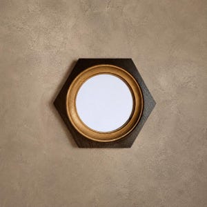 Può includere: Una cornice da parete esagonale caratterizzata da un esterno in legno marrone scuro e un bordo interno circolare con finitura color oro metallizzato. Il centro della cornice contiene un inserto circolare bianco vuoto, offrendo uno spazio chiaro.