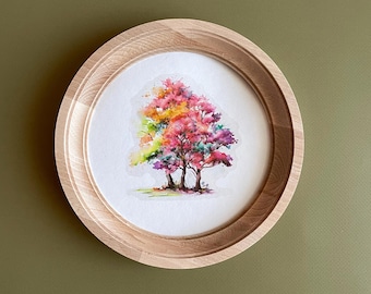May include: A watercolor painting of a tree with vibrant pink, yellow, and purple leaves, set within a round, light-colored wooden frame. The artwork features a detailed depiction of the tree's foliage and trunk, creating a colorful and artistic piece.