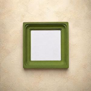 Op de afbeelding: Een vierkante fotolijst met een matte olijfgroene afwerking en een breed, getrapt randontwerp. De lijst heeft een strak, geometrisch silhouet met een gladde oppervlaktestructuur en een gecentreerde, lege witte rechthoekige ruimte voor weergave.