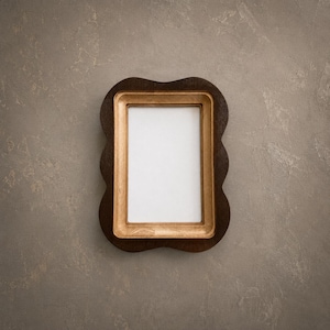 May include: A rectangular picture frame featuring a dark brown outer border with a scalloped edge and a light tan inner border. The frame surrounds a plain white rectangular center area, presenting a clear contrast between the two wood tones.