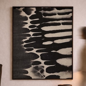 May include: A framed abstract art print in black and white, featuring organic shapes. The artwork hangs above a rustic wooden bench with a small woven stool and a wooden bowl. The room has a neutral color palette.