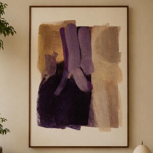 Op de afbeelding: Abstracte kunstprint in een bruine houten lijst. Het kunstwerk toont penseelstreken in paars, bruin en beige op een witte achtergrond. Een houten bankje herbergt boeken, een vaas en een lamp. Een potboom staat links.