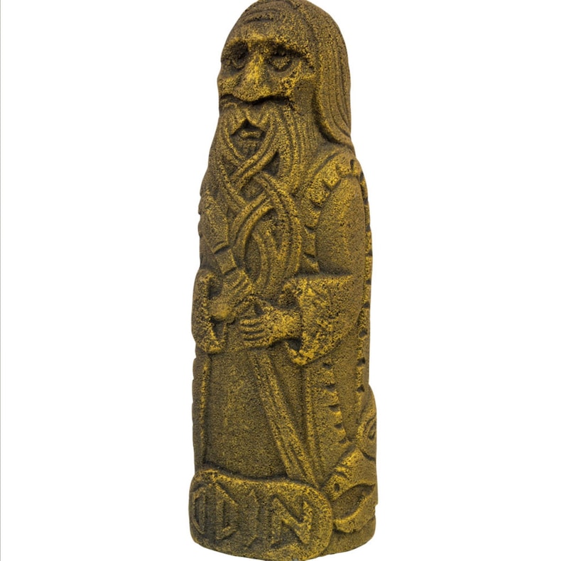 Puede incluir: Una estatua de piedra de color dorado que representa a un hombre barbudo con tallas intrincadas. La estatua est&aacute; de pie y tiene la palabra "ODIN" tallada en la parte inferior.