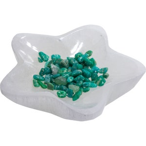 Puede incluir: Un plato de selenita blanco en forma de estrella lleno de virutas de aventurina verde.