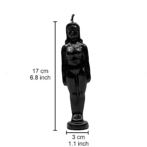 Op de afbeelding: Een zwarte kaars in de vorm van een vrouwelijk figuur, staand op een ronde basis. De kaars is 17 cm hoog en 3 cm breed. De figuur heeft een gedetailleerd gezicht en lichaam, met een lont aan de bovenkant.