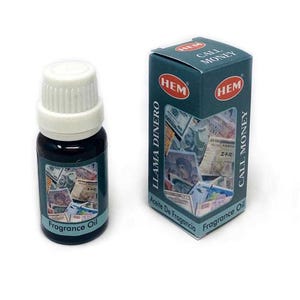May include: A small brown glass bottle with a white cap filled with a clear liquid. The bottle has a label that says "Fragrance Oil" and is surrounded by images of money. The bottle is next to a box with a green background and the text "HEM LLAMA DINERO Aceite De Fragancia" and "HEM CALL MONEY Fragrance Oil".