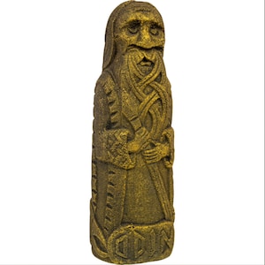 Puede incluir: Una escultura de piedra de color dorado que representa a un hombre barbudo con tallas intrincadas. La escultura es alta y delgada, con una cara detallada y una larga barba. El hombre lleva una t&uacute;nica larga y sostiene un bast&oacute;n en su mano.